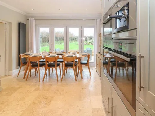 Cottage kitchen with dining table set for eight and view to garden through patio doors