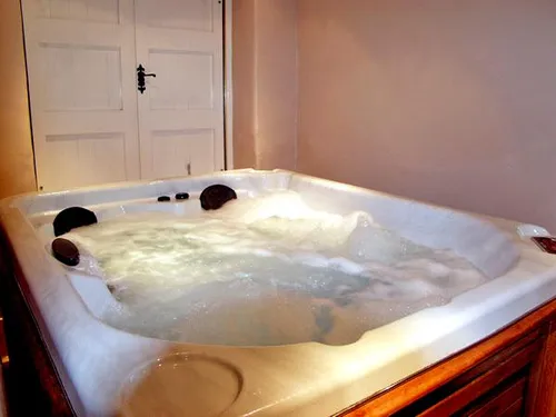 Bubbling hot tub with wooden surround inside The Loft private spa building