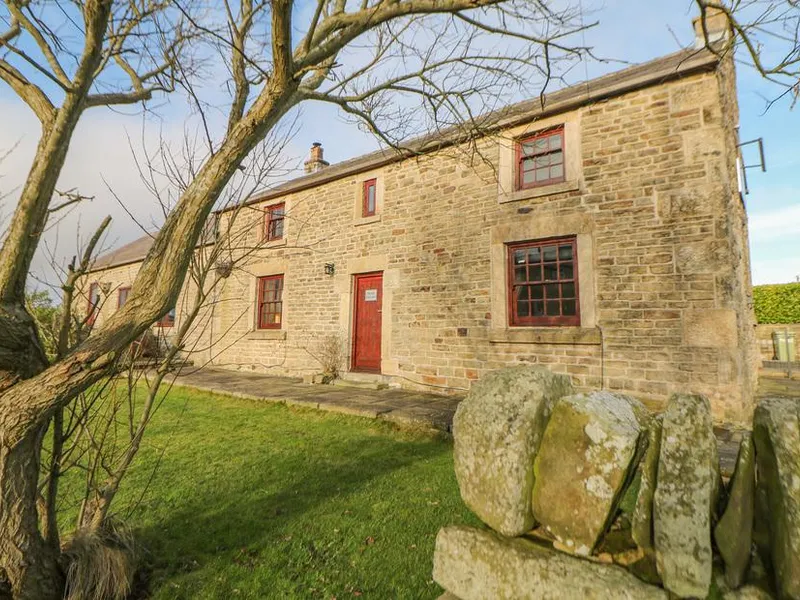 The Old Robin Hood stone coaching inn with red door and windows behind a dry stone wall
