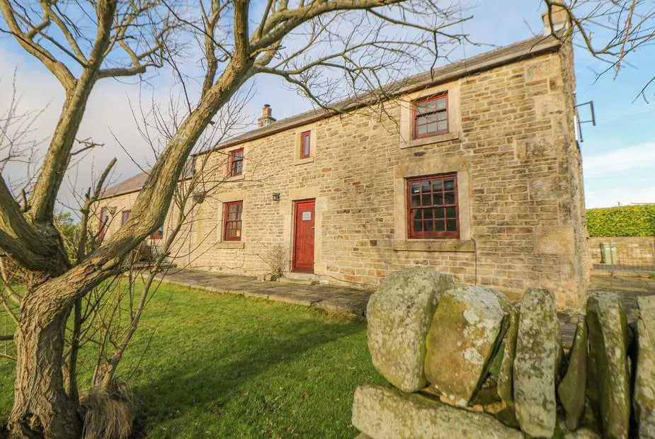 The Old Robin Hood stone coaching inn with red door and windows behind a dry stone wall