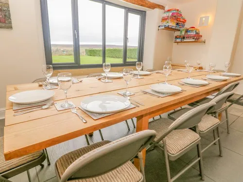 Wooden dining table set for ten with countryside views through patio doors