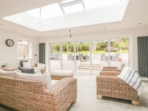 Cottage lounge with wicker sofas and glass doors opening to patio with seating