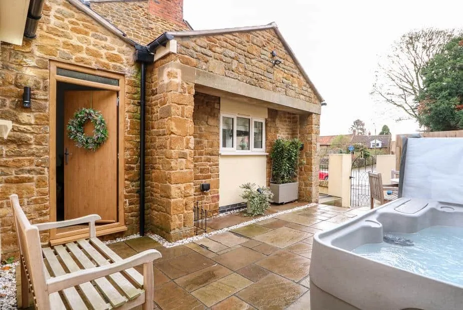 The Pinfold stone exterior with hot tub on a paved patio