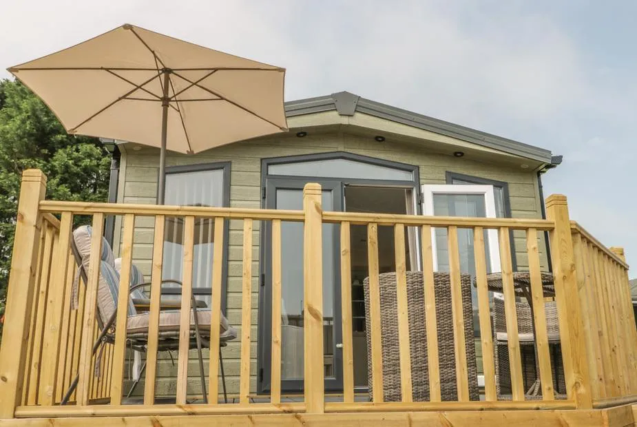 The Sequoia lodge with raised wooden deck, rattan seating, parasol, and French doors