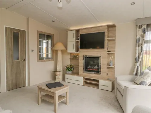 Sitting area with cream sofa, built-in electric fire and TV unit, and patterned curtains