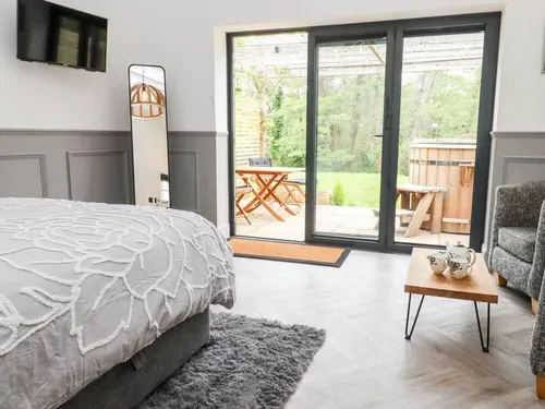 Cottage bedroom with patio doors, outdoor seating and hot tub visible outside