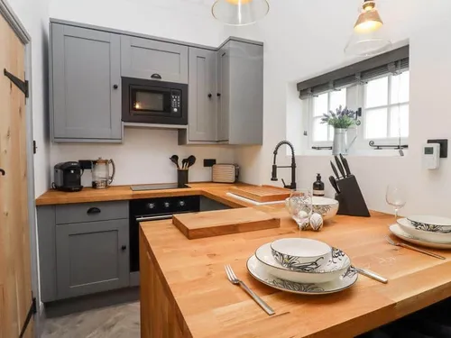 Kitchen with wooden countertop, grey cabinets and dining set for two