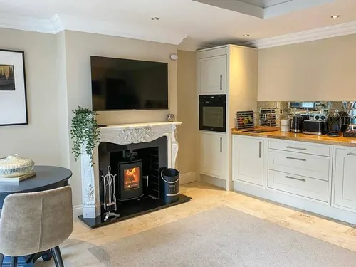 Cottage kitchen with wood burner, TV above mantel and dining table with two chairs