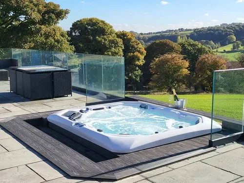 Cottage terrace with hot tub and glass balustrade overlooking countryside