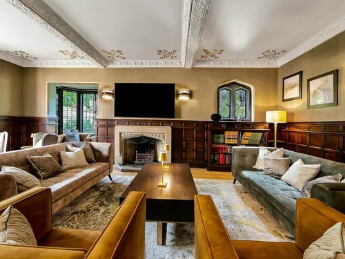 Cottage living room with beamed ceiling, fireplace, sofas, and bookshelves