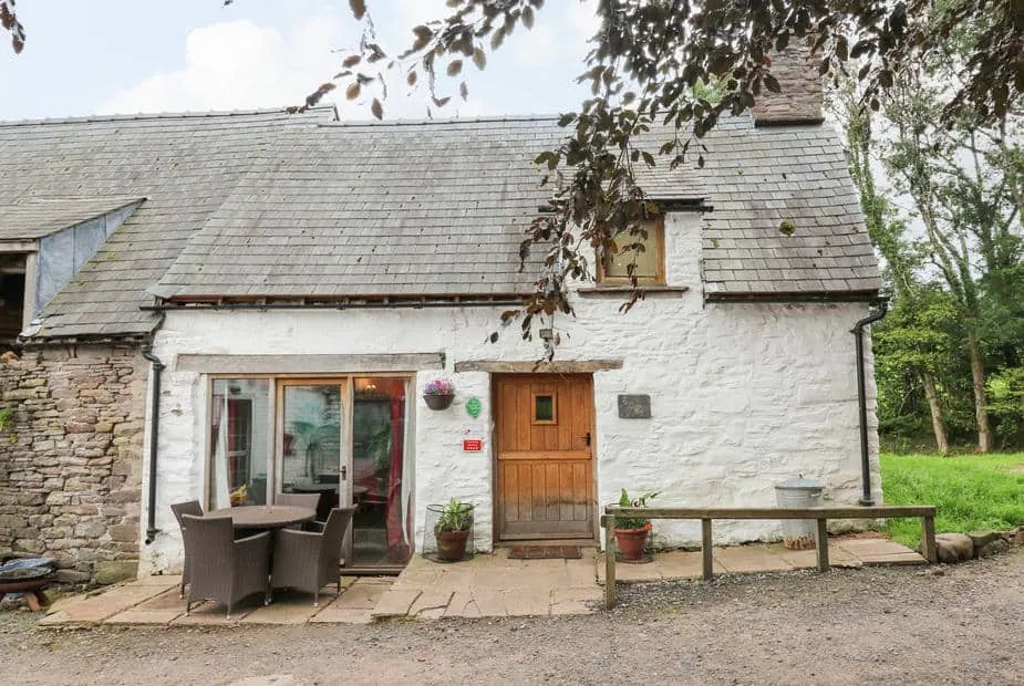 Ty Fferm Hen with stone walls, wooden door and outdoor dining set on patio