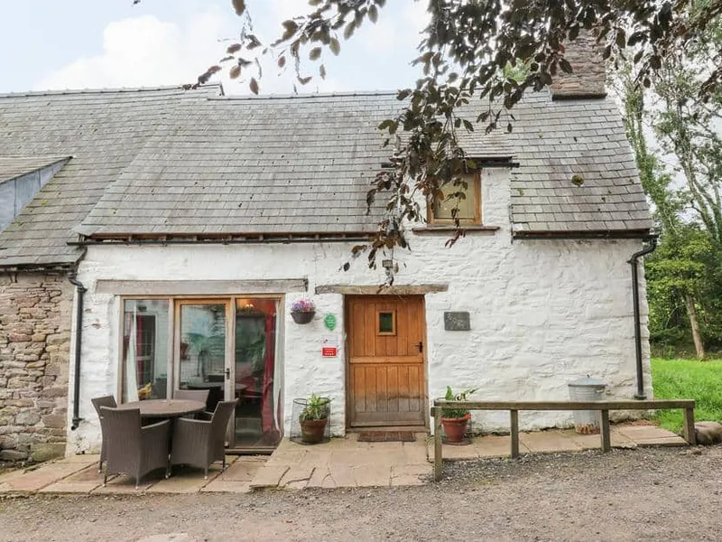 Ty Fferm Hen with stone walls, wooden door and outdoor dining set on patio