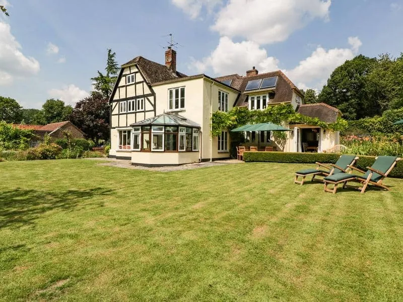 Valley House with conservatory and deck chairs on a large lawn garden