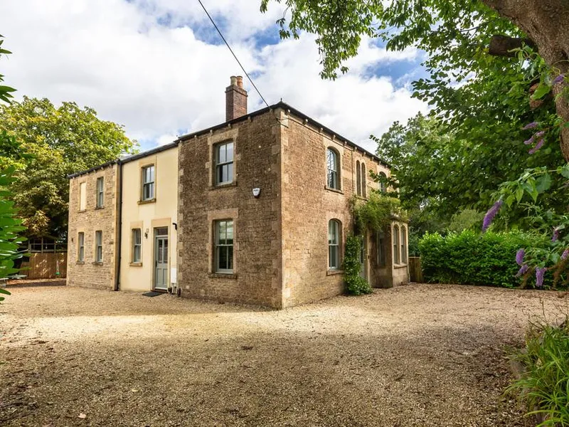 Vallis Oak Villa stone cottage with gravel driveway and mature trees on the edge of Frome