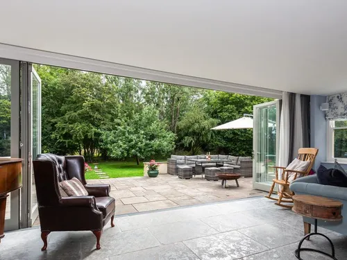 Living room with leather wingback chair and bi-fold doors opening onto patio and garden