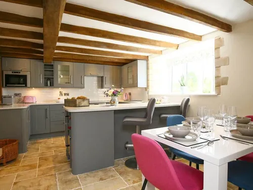 Kitchen with exposed beams, dining table and breakfast bar with chairs