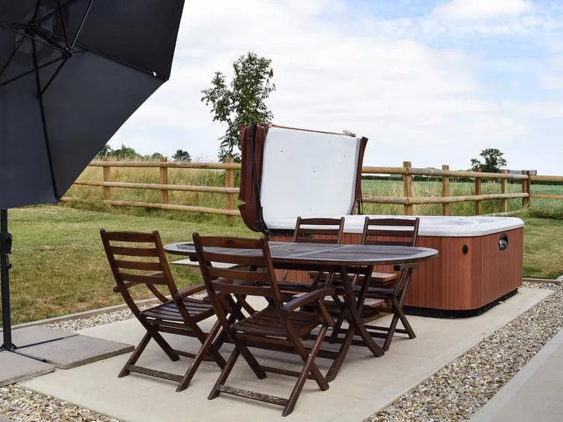 Outdoor seating and hot tub on patio at Waxwing Cottage with countryside views