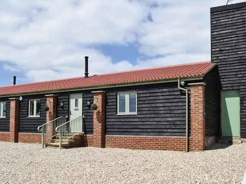 Cottage exterior with black timber cladding, red roof tiles and gravel driveway