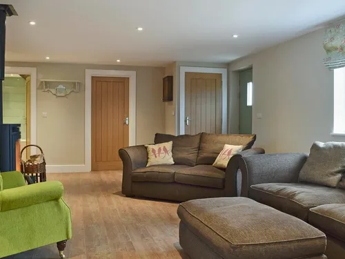 Cottage living room with wood burner, sofas and a green armchair