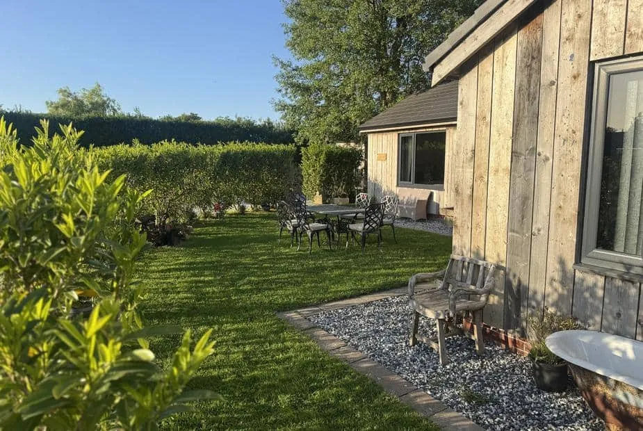Wayside Lodge exterior with wooden cladding and garden seating area on lawn.