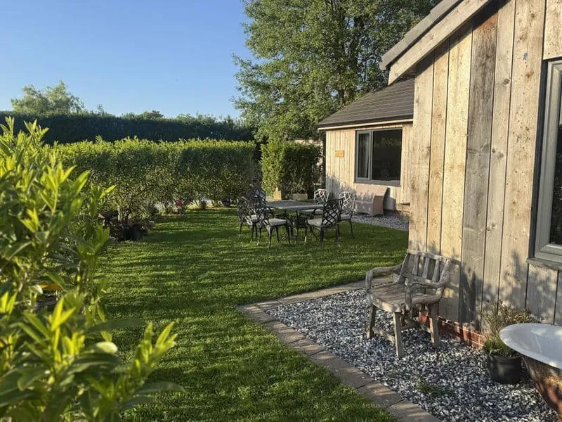 Wayside Lodge exterior with wooden cladding and garden seating area on lawn.