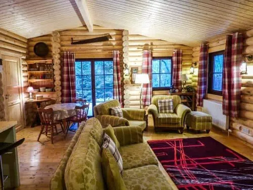 Lodge living room with green sofas, dining table and log walls
