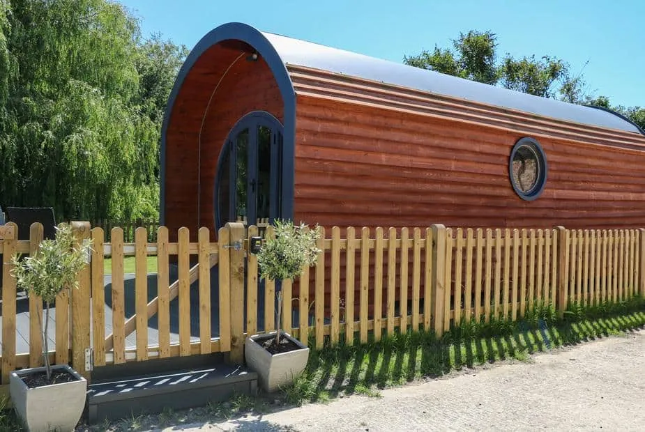 Willow Pod arched timber cabin with picket fence and potted plants at entrance
