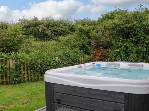 Lodge garden with outdoor hot tub and wooden picket fence