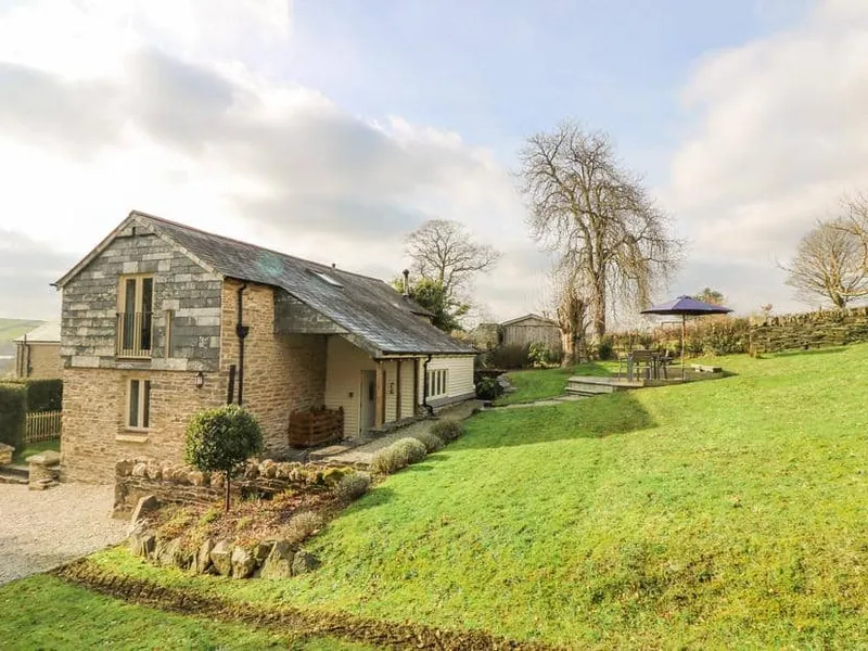 Woodfield Coach House with stone exterior and outdoor seating area on a large lawn