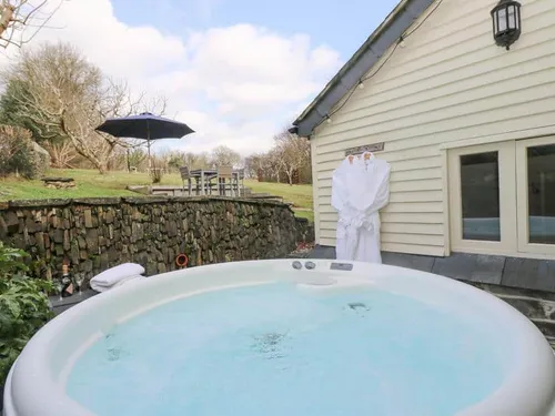 Cottage garden with outdoor hot tub and robes hanging by the wall