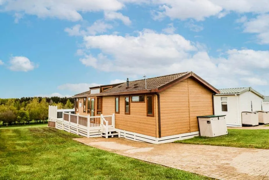 Woodland View Lodge with decking, set on grassy grounds beside other lodges