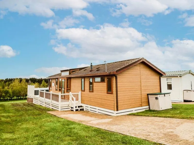 Woodland View Lodge with decking, set on grassy grounds beside other lodges