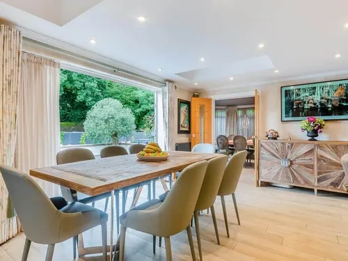 Cottage dining room with wooden table, chairs, and doors open to garden patio