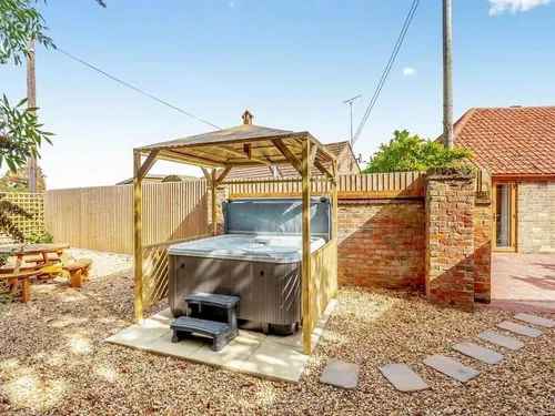 Cottage garden with covered hot tub and picnic bench on gravel patio