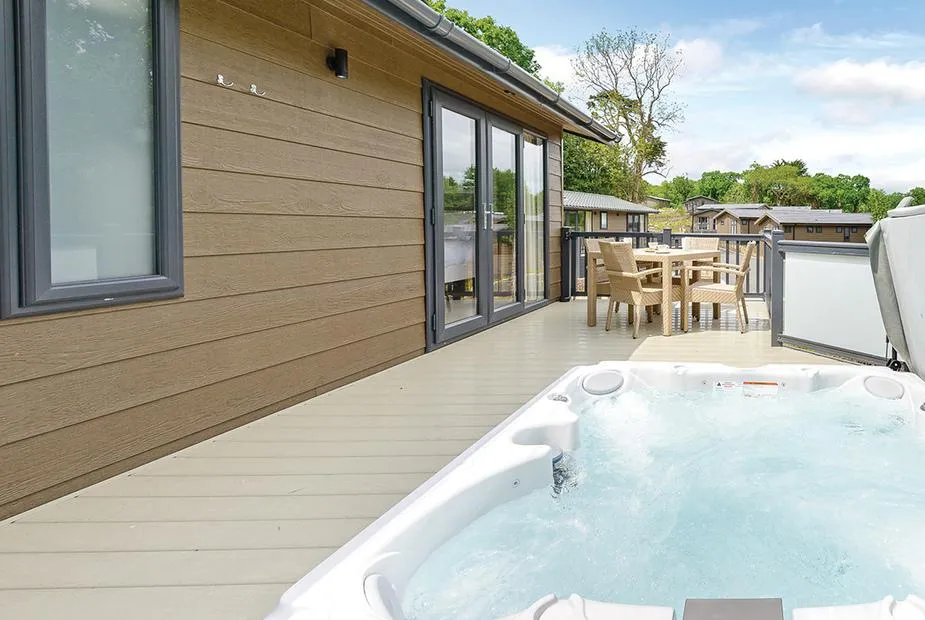 Yaverland Premier lodge deck with outdoor hot tub and dining table overlooking nearby lodges