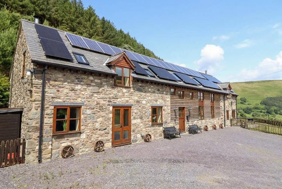 Ysgubor Pwlliago stone cottage exterior with solar panels and countryside views