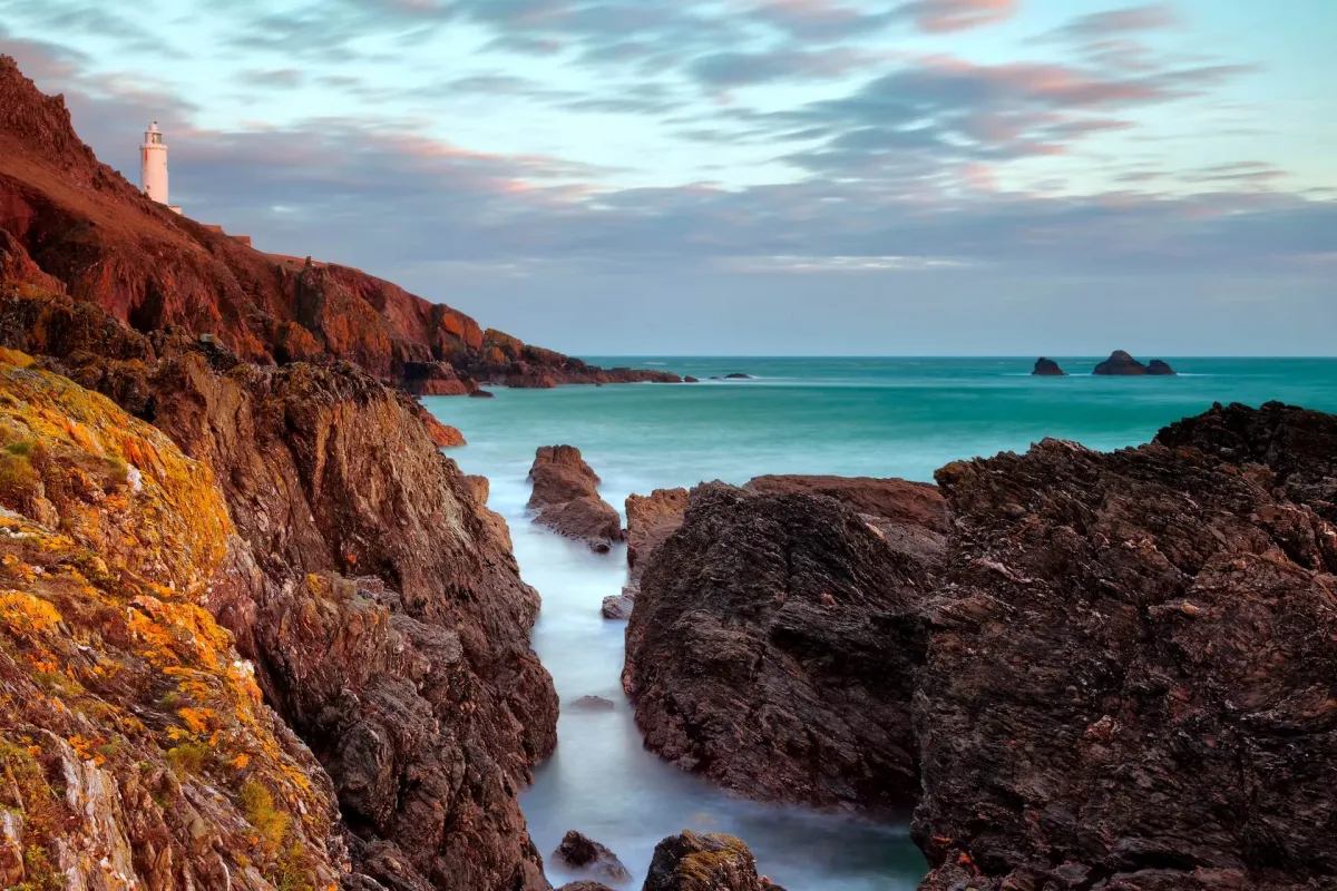 Dramatic coastline at Start Point in South Devon, featuring a white lighthouse perched on the cliffs overlooking the sea.